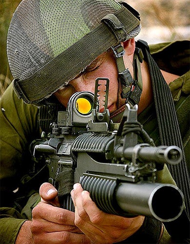 Un soldado usando una mira reflex.
