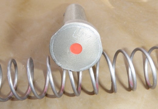 Buffer and buffer spring. The buffer tube has three vent ports at the rear and the buffer is marked HK on the tube face with a red dot in the center as well. The buffer spring is marked with red to distinguish it from a M16A4 or M4 buffer spring.