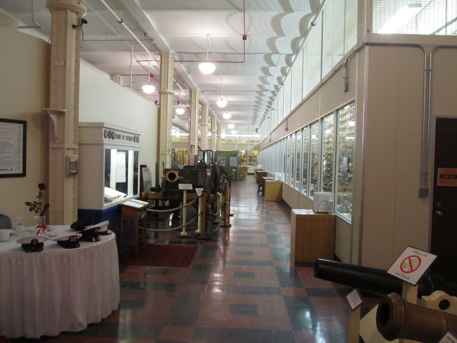 The entrance to the main exhibit hall in the museum. The entire wall on the right and at the rear is completed stacked from floor to ceiling with firearms on display. Descriptions of the various small arms are incorporated within the binders on the right on the various tables. 