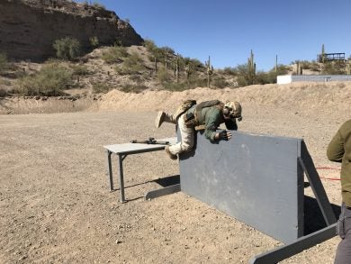 A competitor at Desert Brutatlity 2 Gun match moving over a wall.