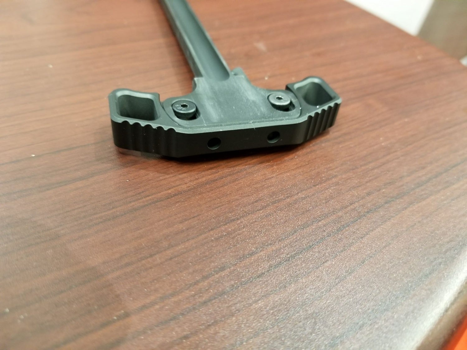 The head of the charging handle is secured by 2 pivoting screws.