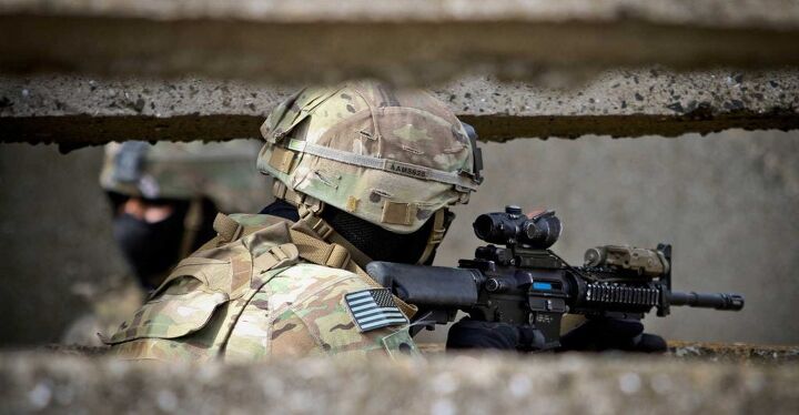 A soldier employing an M4 in a typical modern configuration, equipped with an ACOG optic and PEQ-15 infrared laser.